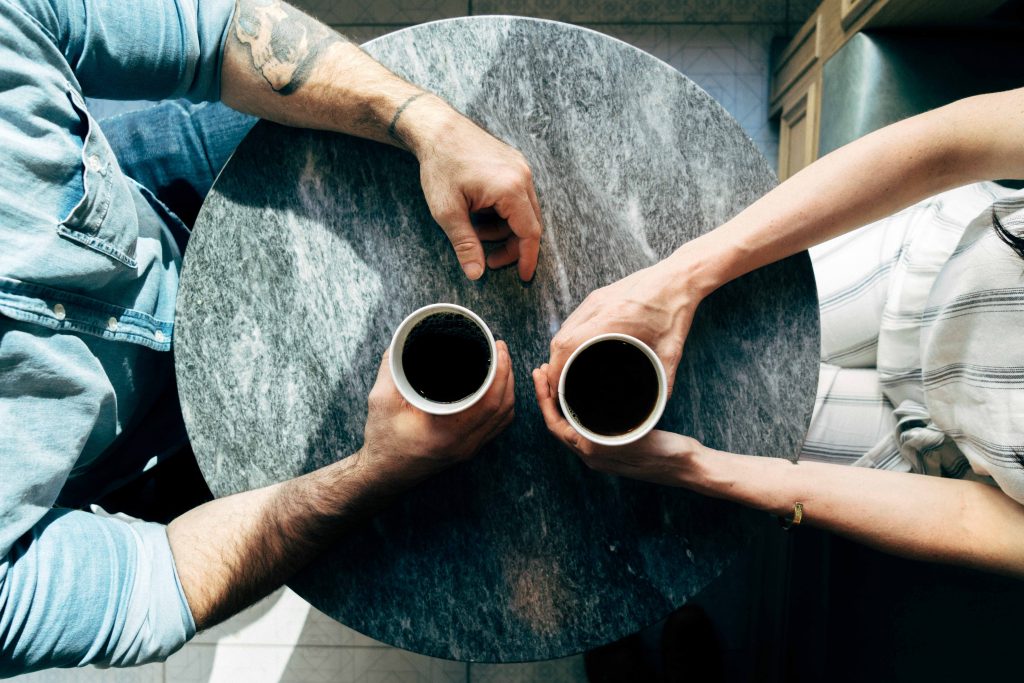 birds eye view of two people at a table sharing a cup of black coffee