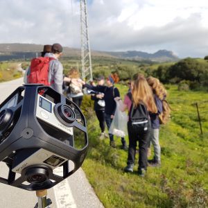 Close up of camera rig with blurred group of students by a roadside in the background