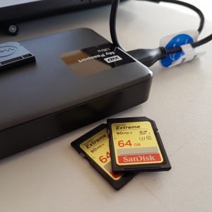 Two memory cards and an external hard drive on a table top. 