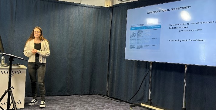 A young woman - Irati, standing in front of a screen while she presents her study.