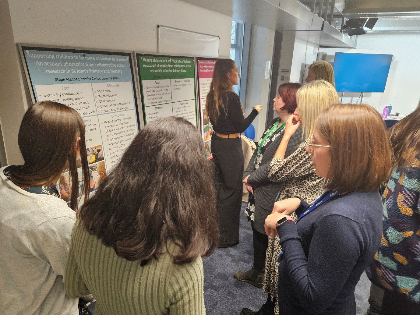 A group of people looking at posters along the walls and speaking with each other