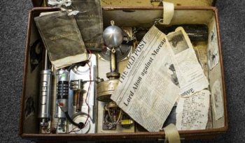 A battered old suitcase, which is open to revealing an assortment of clues