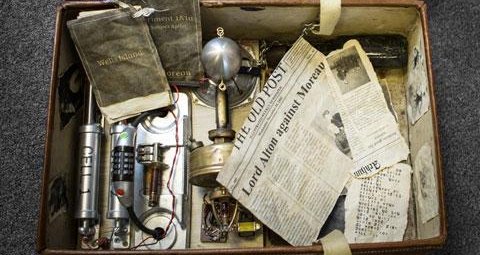 A battered old suitcase, which is open to revealing an assortment of clues