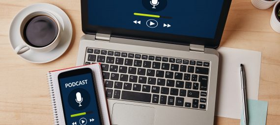 Podcast concept on laptop and smartphone screen over wooden table.