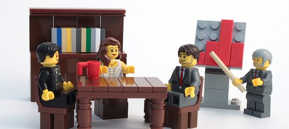 Studio shot of Lego minifigures set up as if having a board meeting and analyzing a chart.