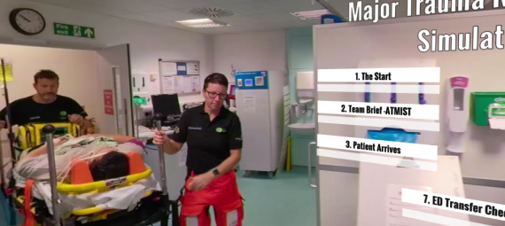 A screen shot of a video showing paramedics pushing a hospital trolley