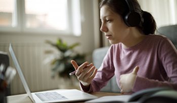 Teenage girl with headphones having an online school class at home.