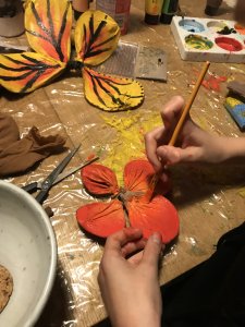 a participant creates a monarch butterfly during an online workshop, using an old pair of tights, wire, and paint.