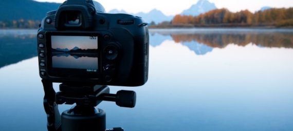 Camera on tripod filming a view of a lake and mountains