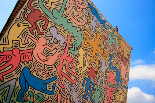 A vibrant painting of multi-coloured figures. The theme of this mural is that of peace and harmony in the world.