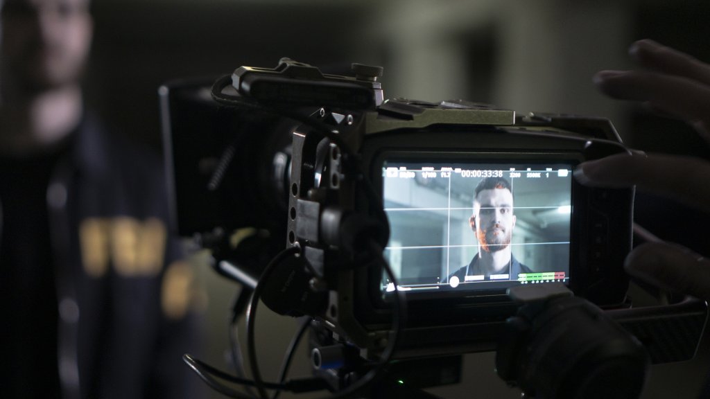 A close up on a camera monitor showing a person being filmed.