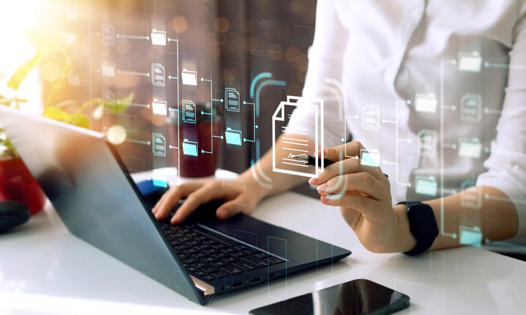 A high tech image of a laptop with projected icons and a person interacting with them.