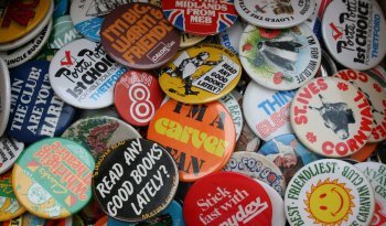 A collection of badges piled on top of each other, the badges are retro in their design.