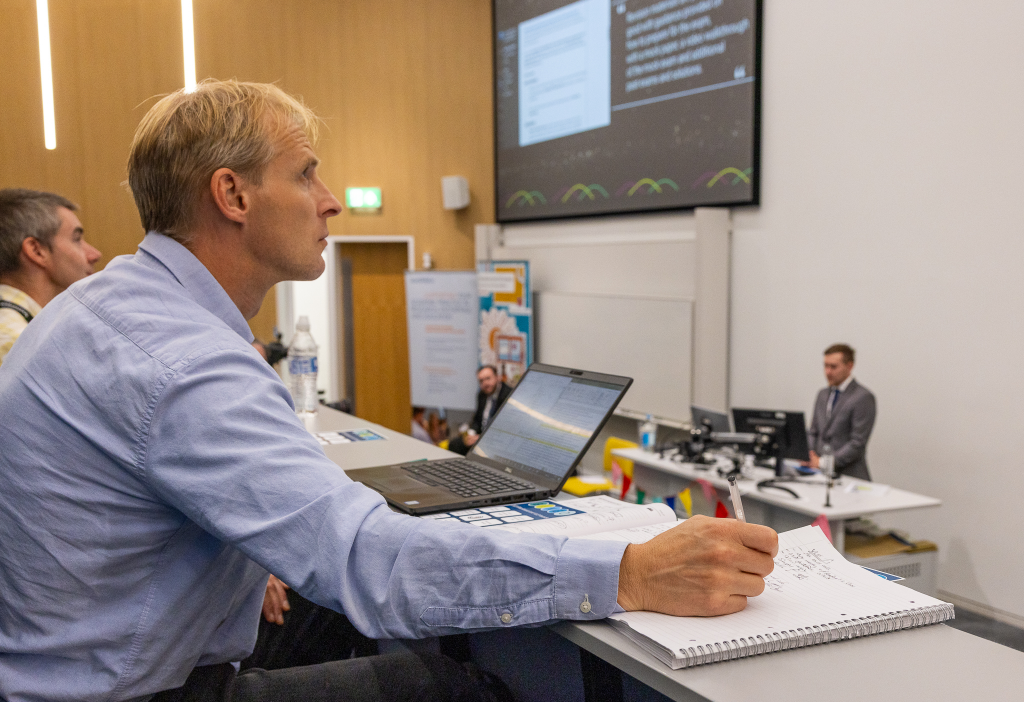 A person watching a course highlight video and making notes. 