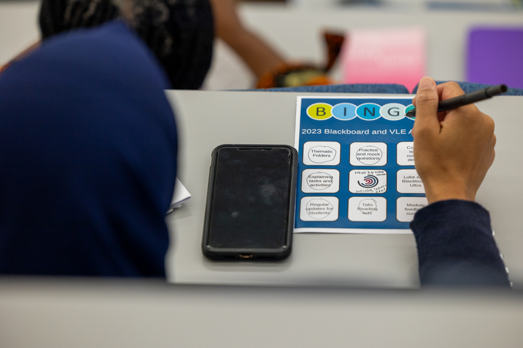 A person filling out a course design bingo card. 
