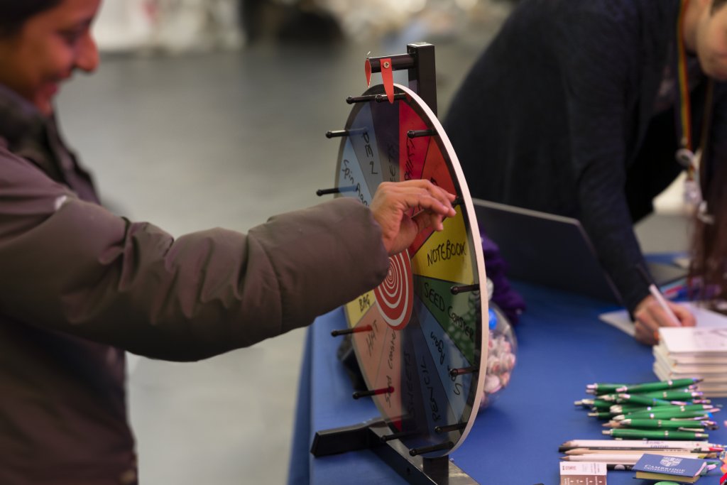 A student is standing at the table for the DigiSkills event. They are spinning the lucky dip prize wheel.