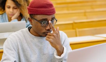 students sitting at the desks in a lecture hall with laptops