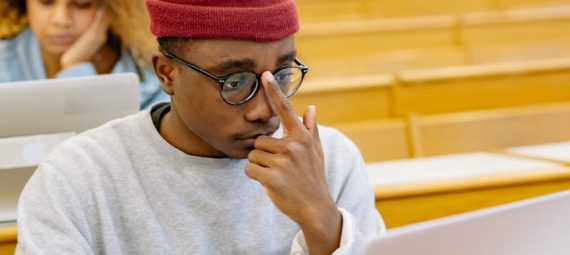 students sitting at the desks in a lecture hall with laptops