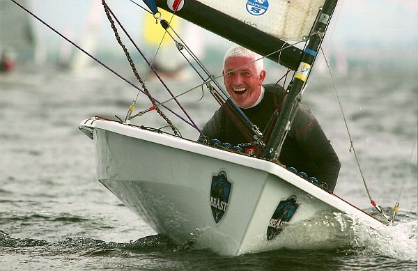 A happy grey haired man enjoying sailing a small one person topper style sailboat named Beast.