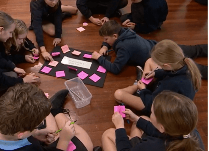 Children sat on the floor working on post-it notes