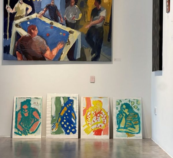 A large painting of people around a pool table hangs on a white wall, with four colorful abstract portraits displayed on the floor beneath it.